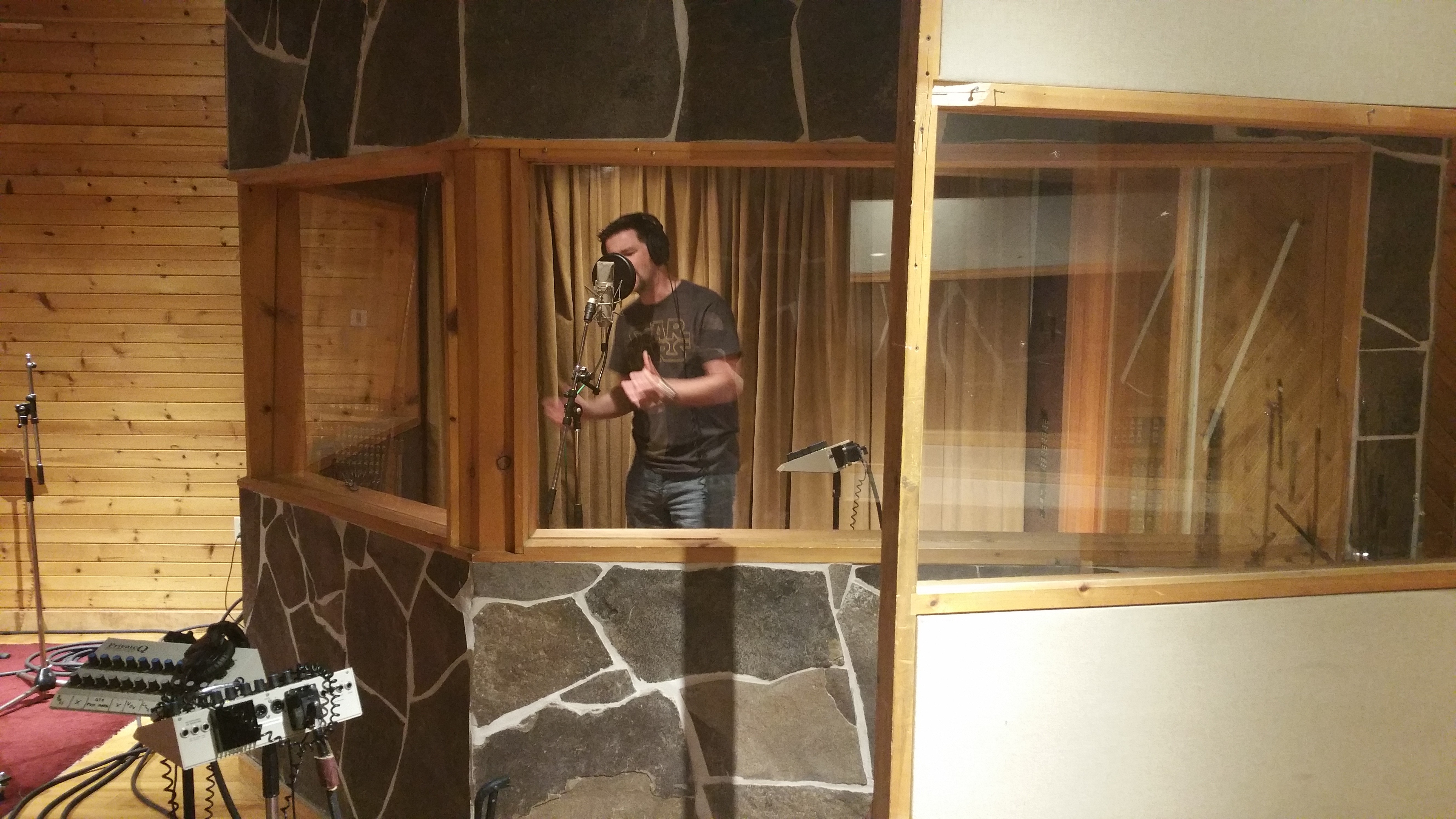 James Downham singing into a microphone in a recording studio.